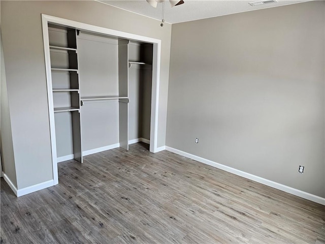 unfurnished bedroom with hardwood / wood-style flooring, ceiling fan, and a closet