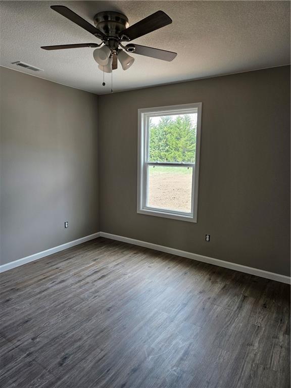 empty room featuring ceiling fan, dark hardwood / wood-style flooring, and a textured ceiling