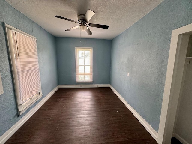 spare room with a textured ceiling, ceiling fan, and dark wood-type flooring