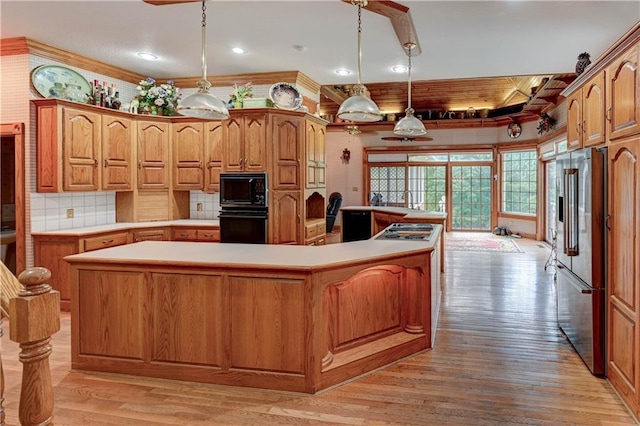 kitchen featuring a center island, light hardwood / wood-style floors, black appliances, pendant lighting, and tasteful backsplash