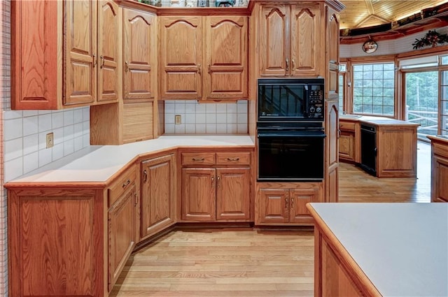 kitchen with backsplash, black appliances, and light hardwood / wood-style floors