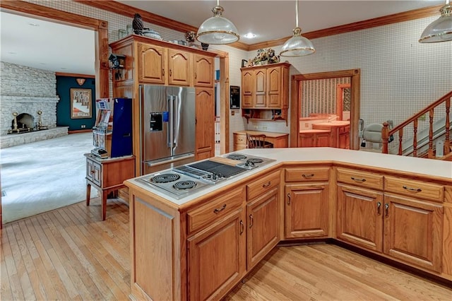 kitchen with crown molding, pendant lighting, a fireplace, appliances with stainless steel finishes, and light hardwood / wood-style flooring