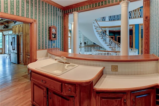 interior space with light wood-type flooring, high quality fridge, ornate columns, and sink