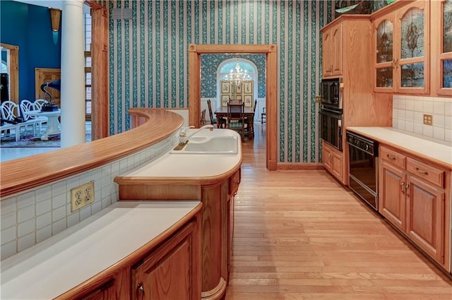 kitchen featuring black appliances, decorative backsplash, a chandelier, and light hardwood / wood-style flooring