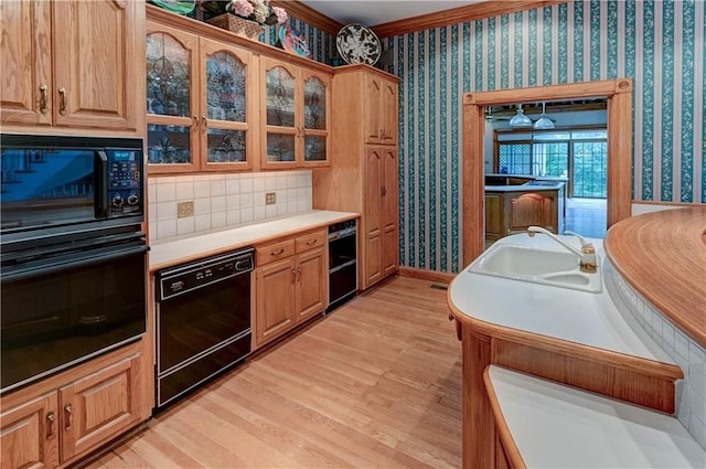 kitchen with black appliances, ornamental molding, sink, and light hardwood / wood-style floors