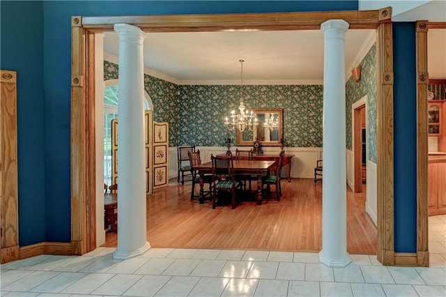 dining area featuring a chandelier, ornamental molding, light tile patterned flooring, and ornate columns