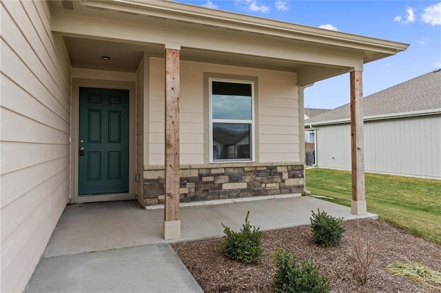 entrance to property featuring a lawn and a porch