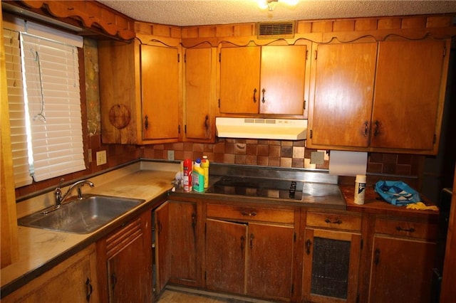 kitchen featuring backsplash, sink, a textured ceiling, and black cooktop