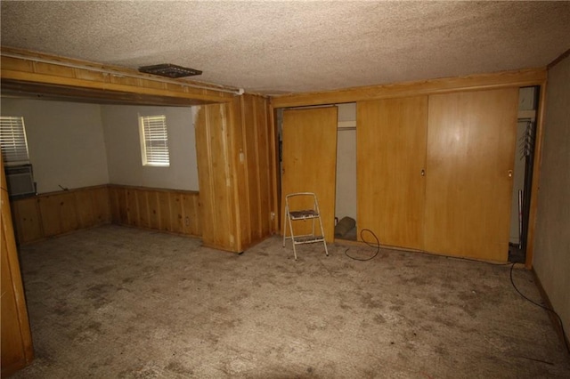 unfurnished room with carpet, a textured ceiling, and wood walls