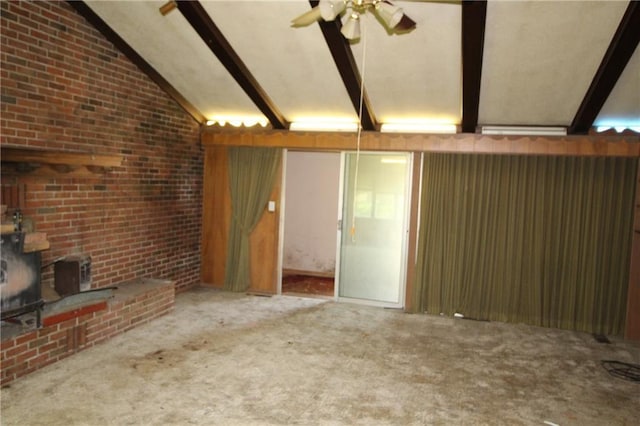 unfurnished living room featuring carpet floors, lofted ceiling with beams, ceiling fan, and brick wall