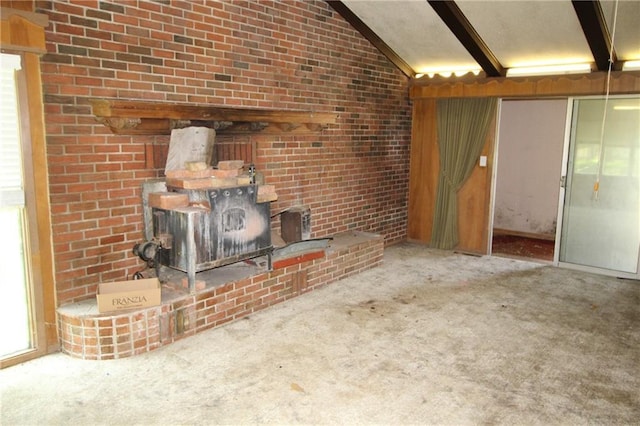 unfurnished living room with brick wall, carpet flooring, and lofted ceiling with beams