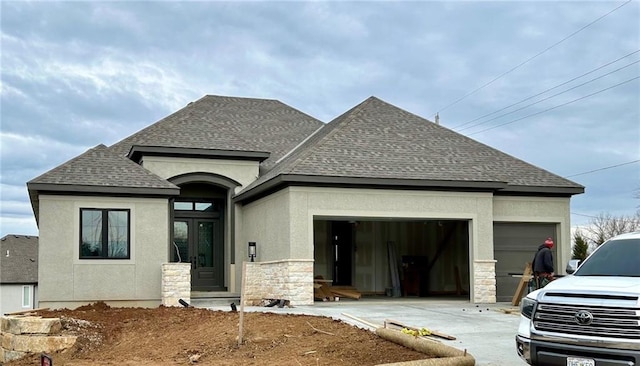 view of front of property with a garage, driveway, stone siding, roof with shingles, and stucco siding