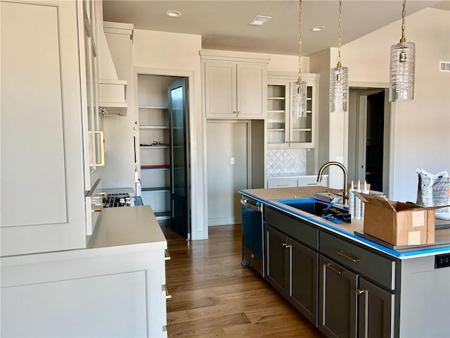 kitchen featuring glass insert cabinets, white cabinetry, a sink, and an island with sink