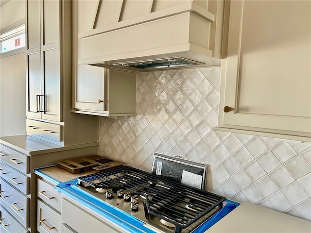 kitchen with premium range hood, stainless steel gas stovetop, light countertops, and backsplash