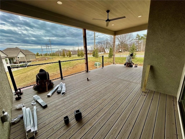 wooden terrace with a ceiling fan and a lawn