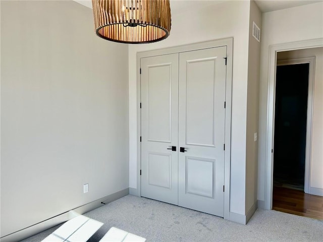 interior space with baseboards, a closet, visible vents, and light colored carpet