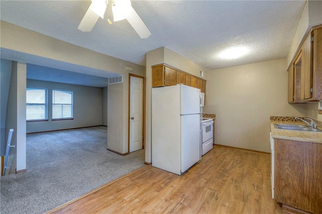 kitchen with sink, white appliances, ceiling fan, light hardwood / wood-style floors, and a textured ceiling