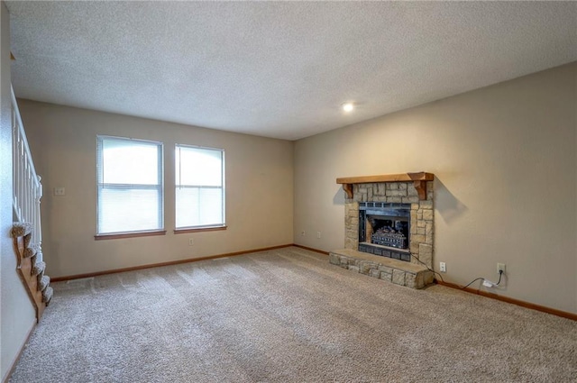 unfurnished living room featuring a stone fireplace, carpet floors, and a textured ceiling