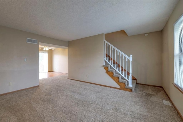 carpeted spare room with plenty of natural light and a textured ceiling