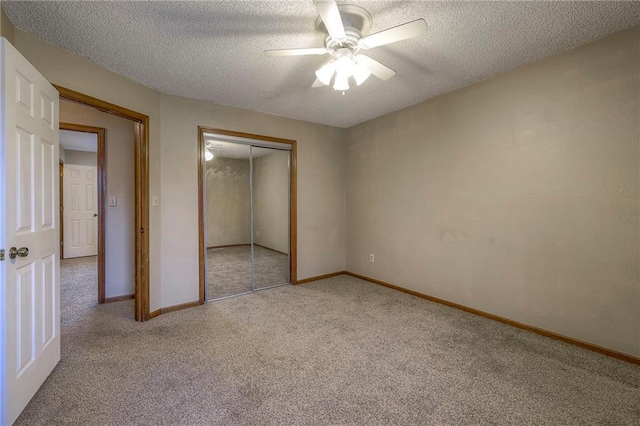 unfurnished bedroom with ceiling fan, light colored carpet, a closet, and a textured ceiling