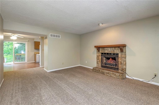 unfurnished living room with ceiling fan, a fireplace, carpet floors, and a textured ceiling