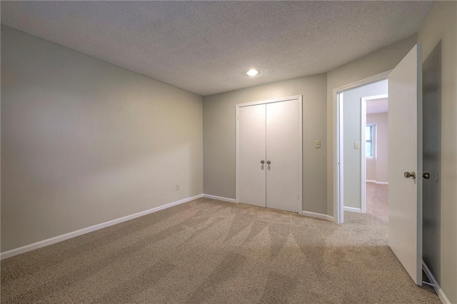 unfurnished bedroom featuring light carpet, a textured ceiling, and a closet