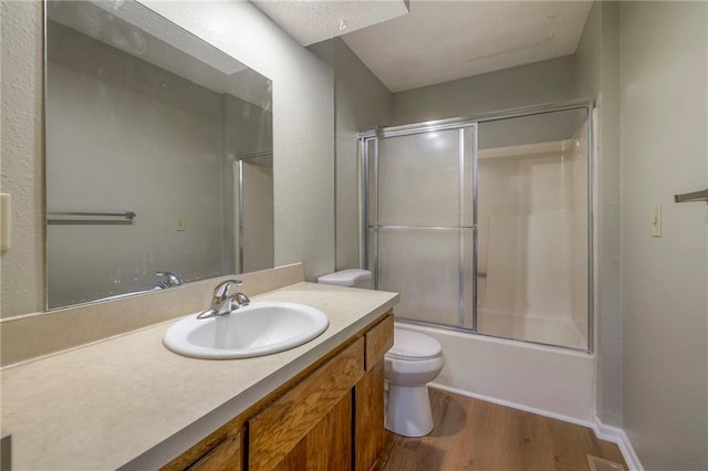 full bathroom featuring vanity, wood-type flooring, enclosed tub / shower combo, and toilet