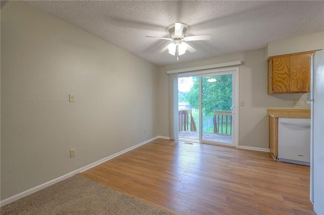 unfurnished dining area featuring ceiling fan, light hardwood / wood-style floors, and a textured ceiling