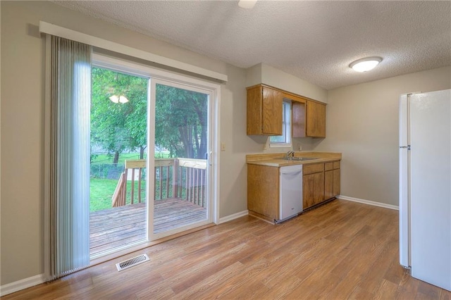 kitchen with sink, white appliances, light hardwood / wood-style floors, and a textured ceiling