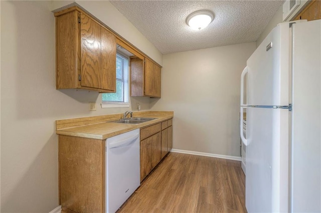 kitchen with sink, white appliances, light hardwood / wood-style floors, and a textured ceiling