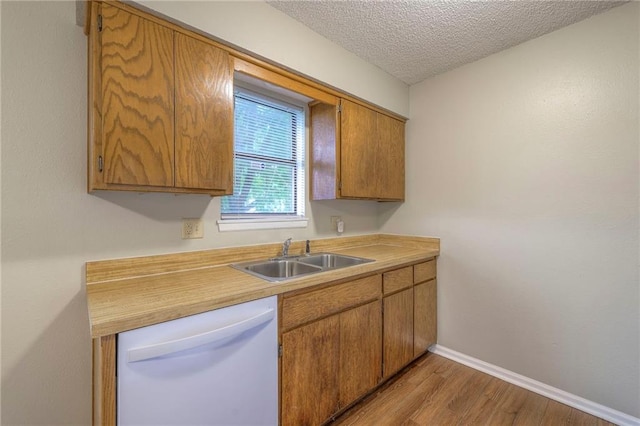 kitchen with dishwasher, sink, a textured ceiling, and light wood-type flooring