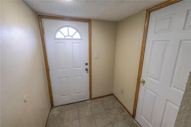 doorway with light tile patterned floors and a textured ceiling