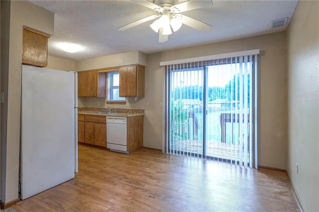 kitchen featuring sink, white appliances, light hardwood / wood-style flooring, a textured ceiling, and ceiling fan