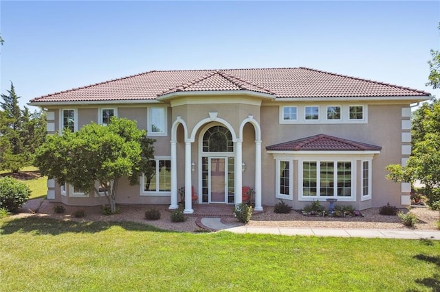 mediterranean / spanish home featuring a tiled roof, a front yard, and stucco siding