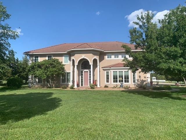 mediterranean / spanish house with stucco siding, a tiled roof, and a front yard