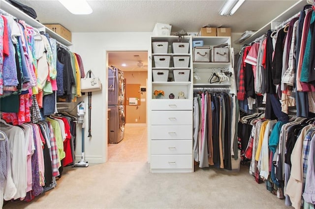 spacious closet featuring stacked washer / dryer and light carpet