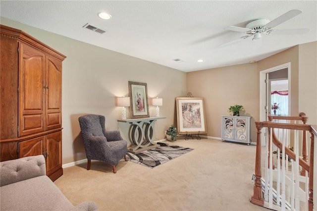 living area featuring light colored carpet and ceiling fan