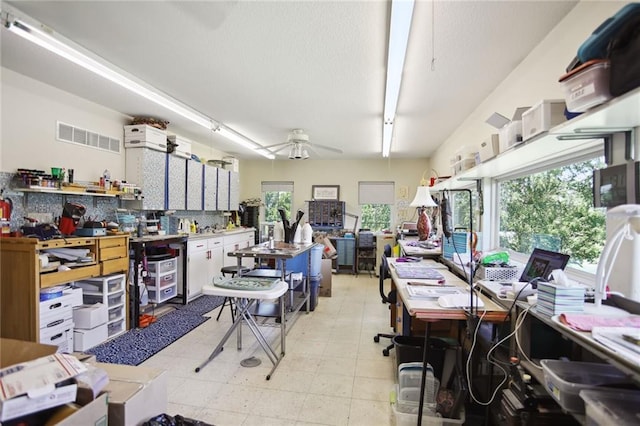 home office featuring visible vents, a ceiling fan, and a workshop area