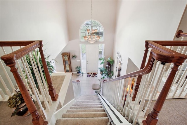 stairs featuring carpet, a towering ceiling, and an inviting chandelier