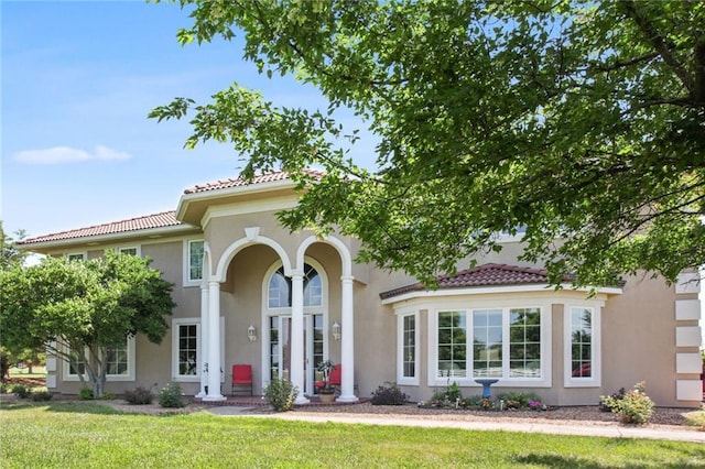 mediterranean / spanish-style home featuring stucco siding, a front yard, and a tiled roof