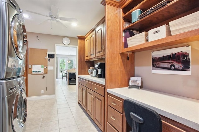 kitchen with brown cabinets, light tile patterned floors, light countertops, stacked washer / dryer, and built in study area