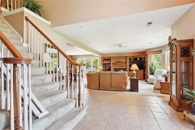 living room featuring light tile patterned floors, stairway, a fireplace, and a healthy amount of sunlight