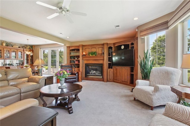 carpeted living room with ceiling fan with notable chandelier and french doors