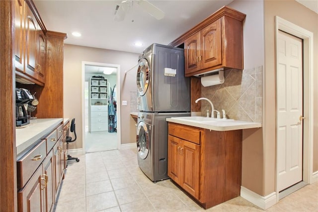 kitchen featuring sink, ceiling fan, light tile patterned floors, tasteful backsplash, and stacked washer / dryer