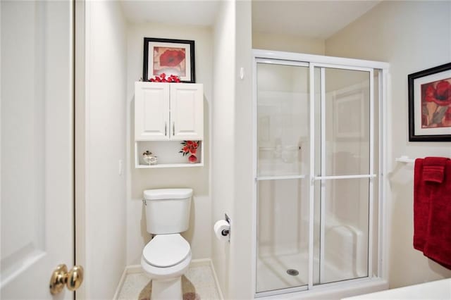 bathroom featuring a shower stall, toilet, and baseboards