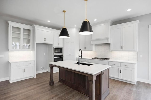 kitchen with stainless steel appliances, sink, pendant lighting, a center island with sink, and white cabinets