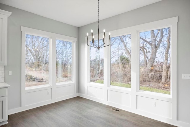 unfurnished dining area featuring dark wood-type flooring and a notable chandelier