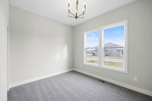 empty room with carpet flooring and a notable chandelier