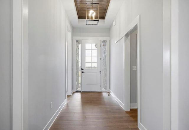 doorway to outside featuring a raised ceiling, wood ceiling, and dark hardwood / wood-style floors