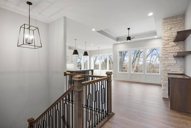 hallway with hardwood / wood-style flooring, a raised ceiling, sink, and an inviting chandelier